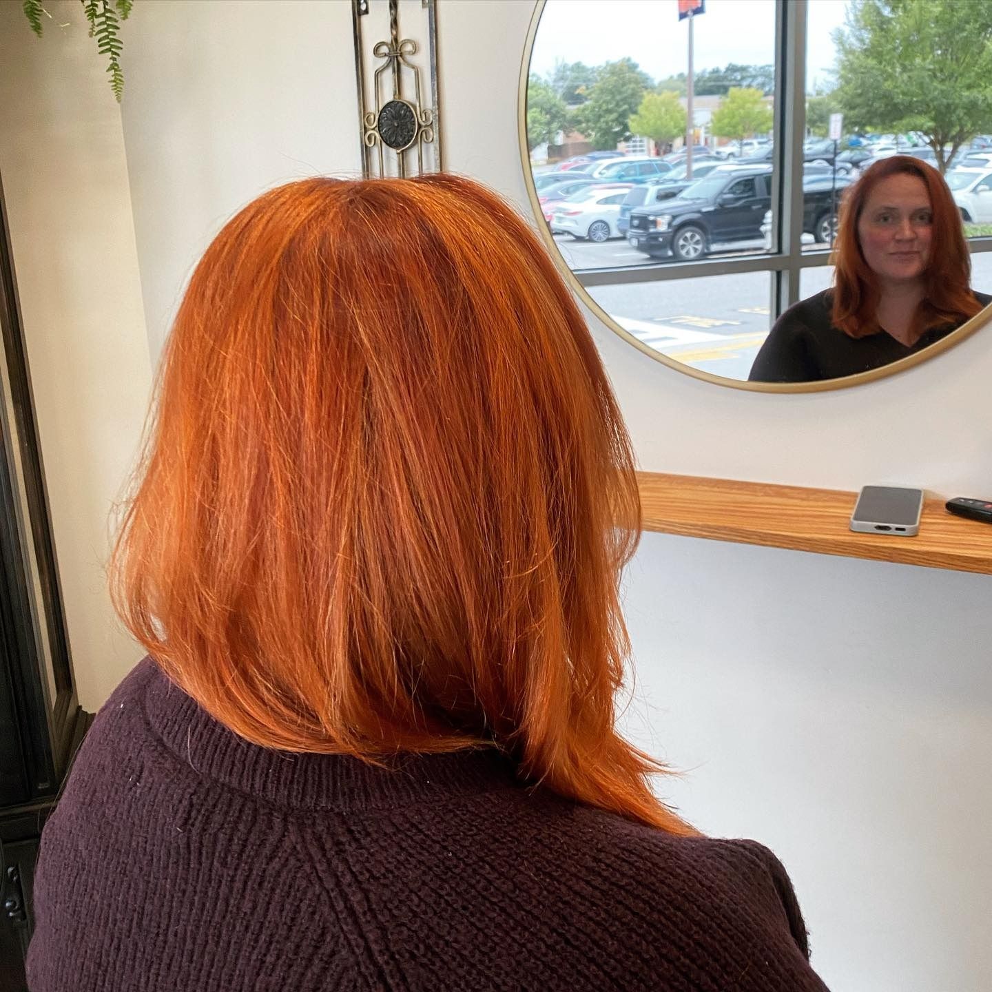 A woman with red hair is looking at her reflection in a mirror.