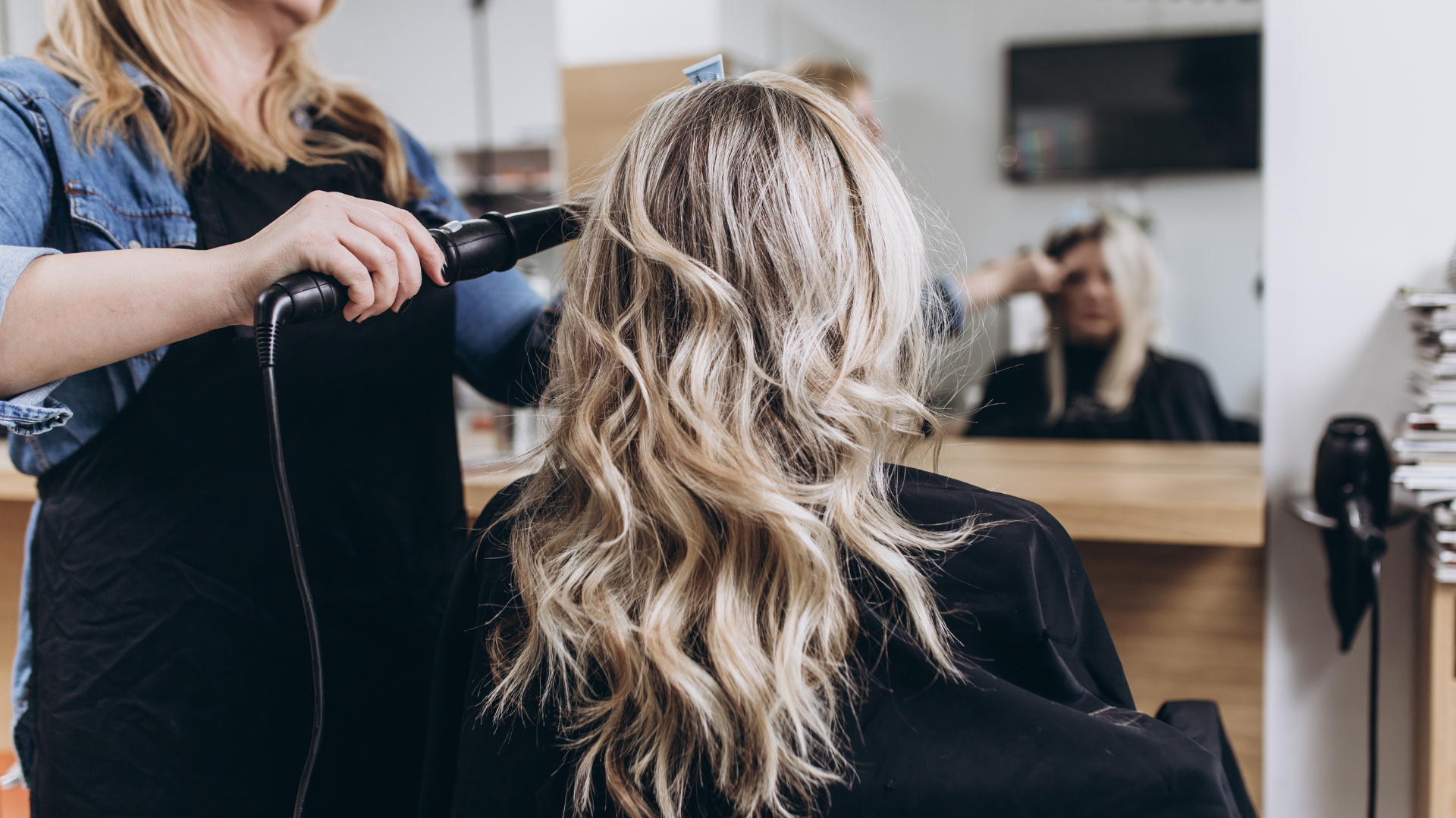 A woman is getting her hair blow dried by a hairdresser in a salon.