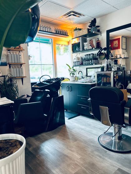 A woman with blonde curly hair is wearing a purple sweater.