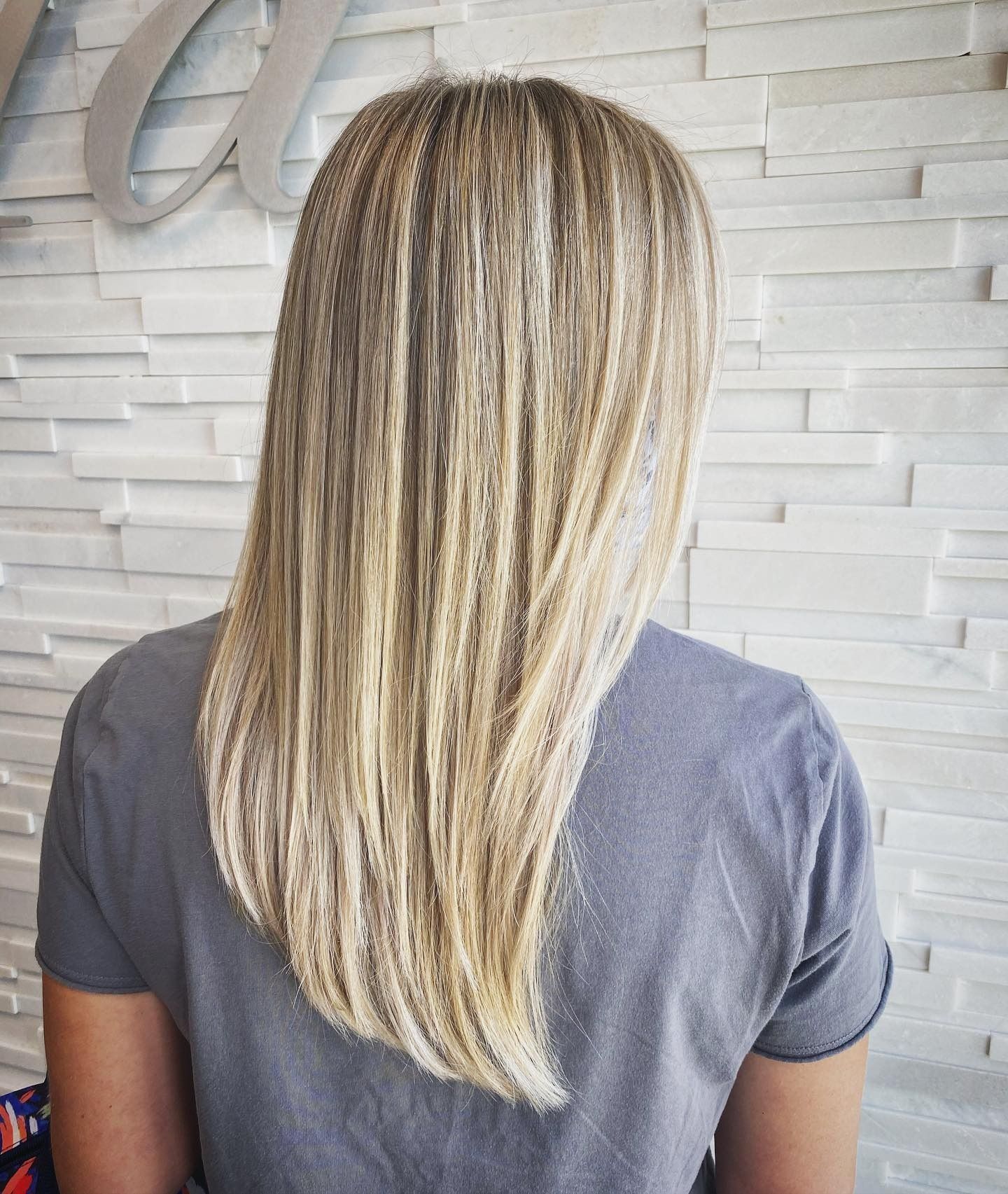 A woman with long blonde hair is wearing a grey shirt.