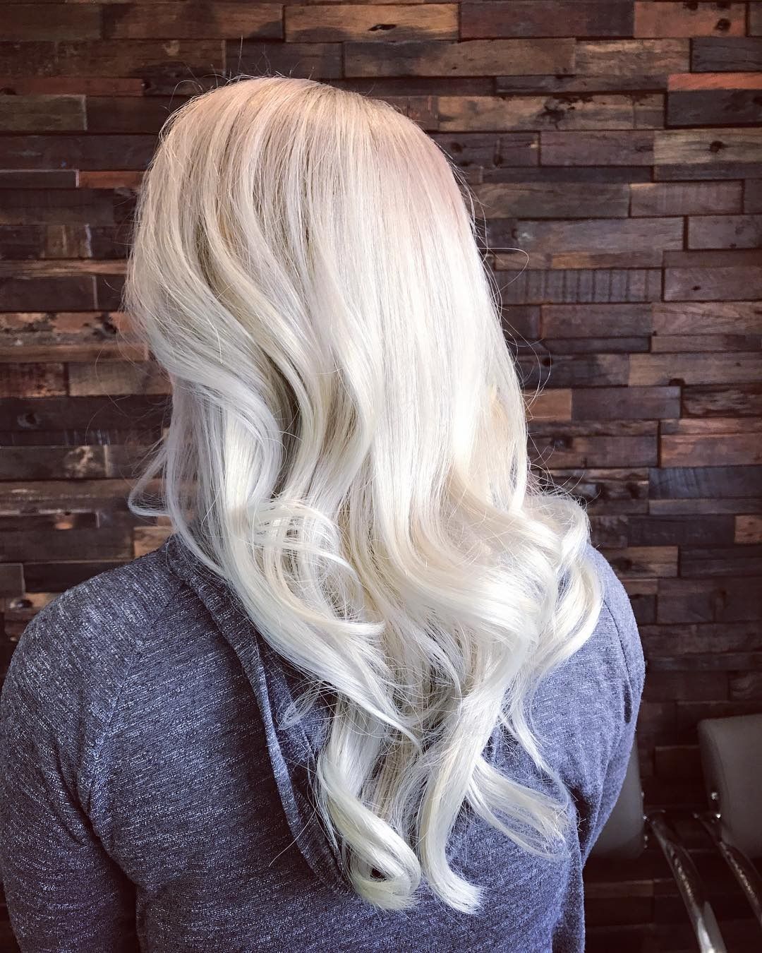 A woman with long blonde hair is wearing a gray hoodie.