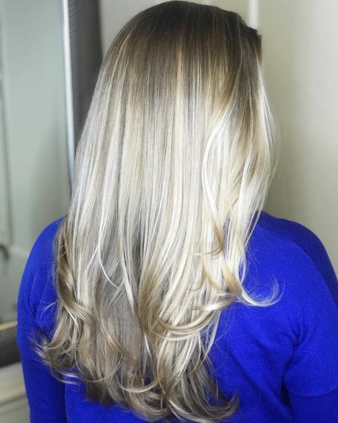 A woman with long blonde hair is wearing a blue shirt.