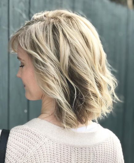 A woman with blonde hair is wearing a white sweater