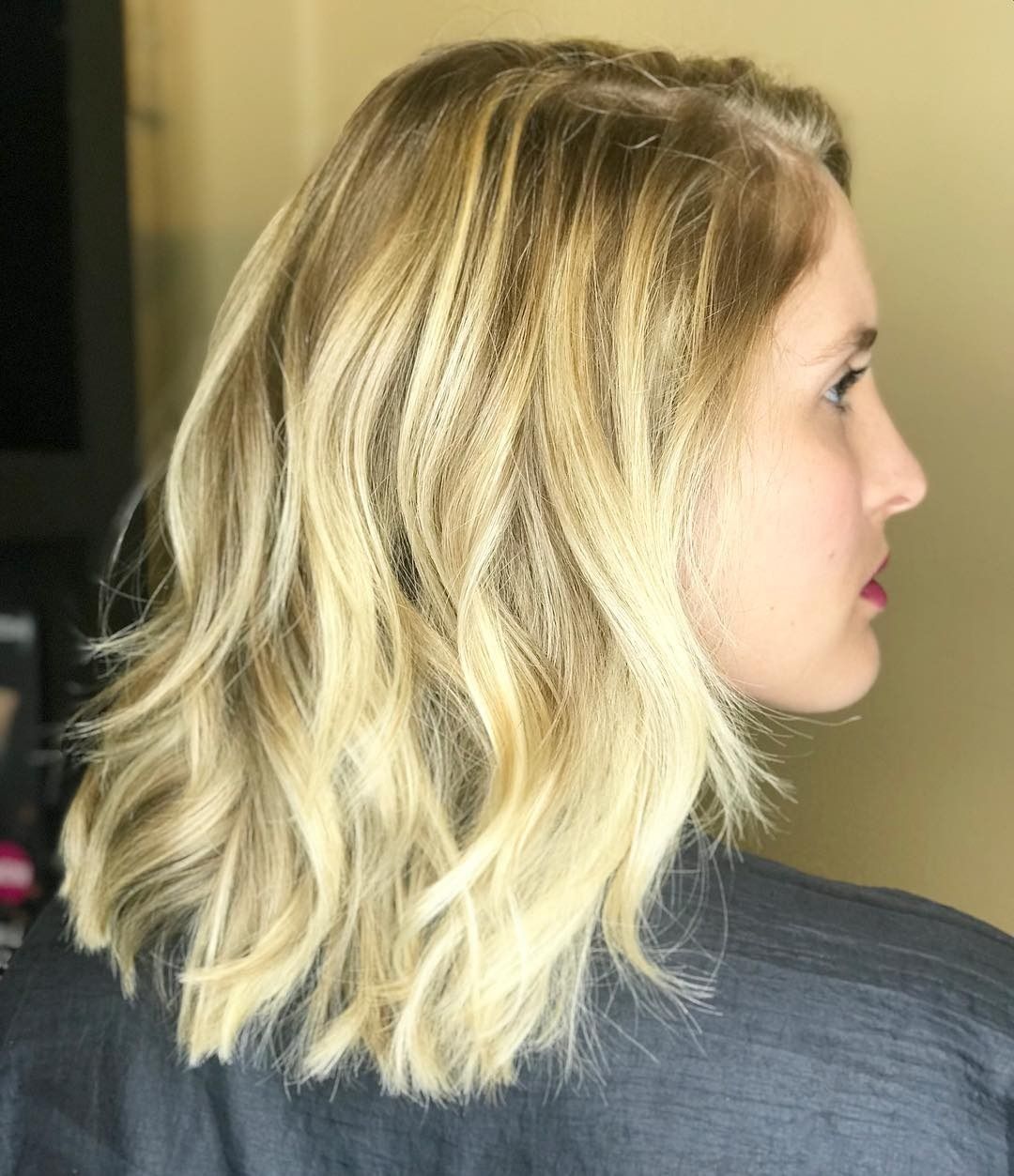 A woman with blonde hair is wearing a gray shirt.