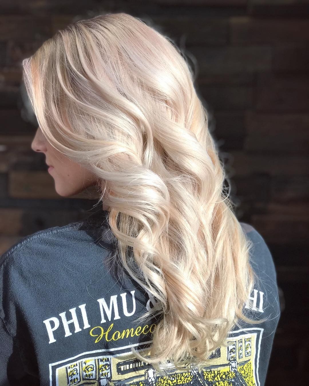 A woman with long blonde hair is wearing a phi mu home shirt.
