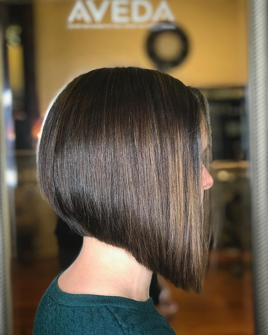 A woman is standing in front of a sign that says aveda