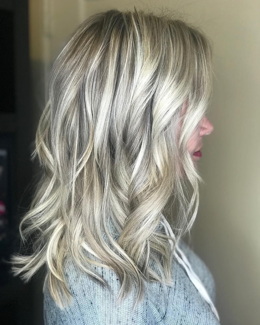 A woman with long blonde hair is wearing a grey sweater.