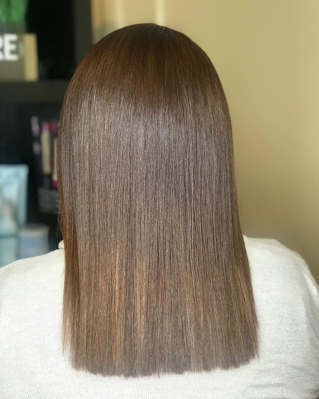 A woman with long brown hair is wearing a white shirt.