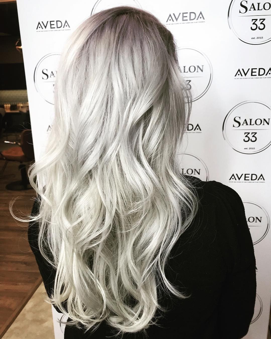 A woman with long gray hair is standing in front of a sign that says salon 33.
