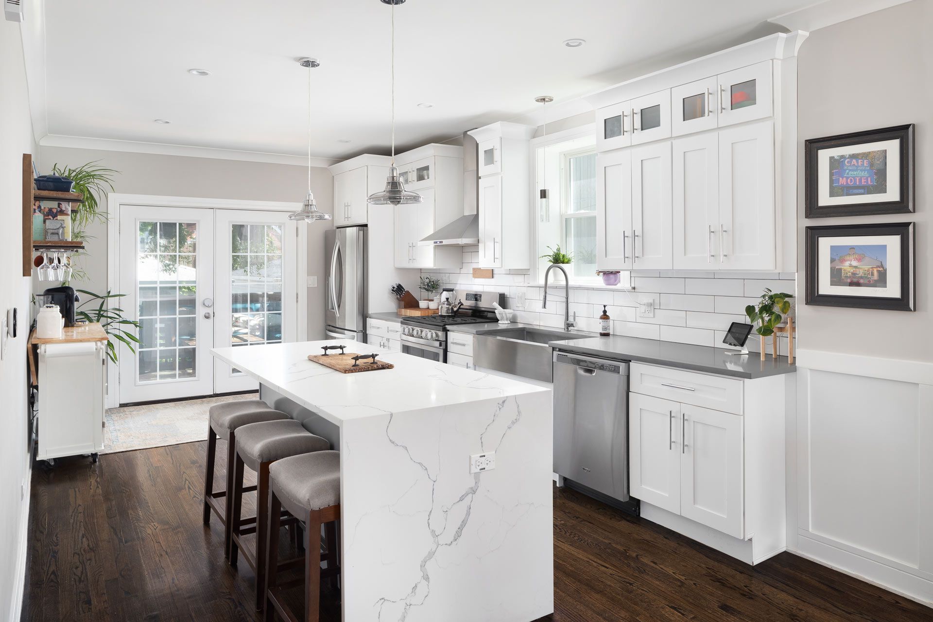 Bright white kitchen with island, stainless steel appliances, and dark wood floors.