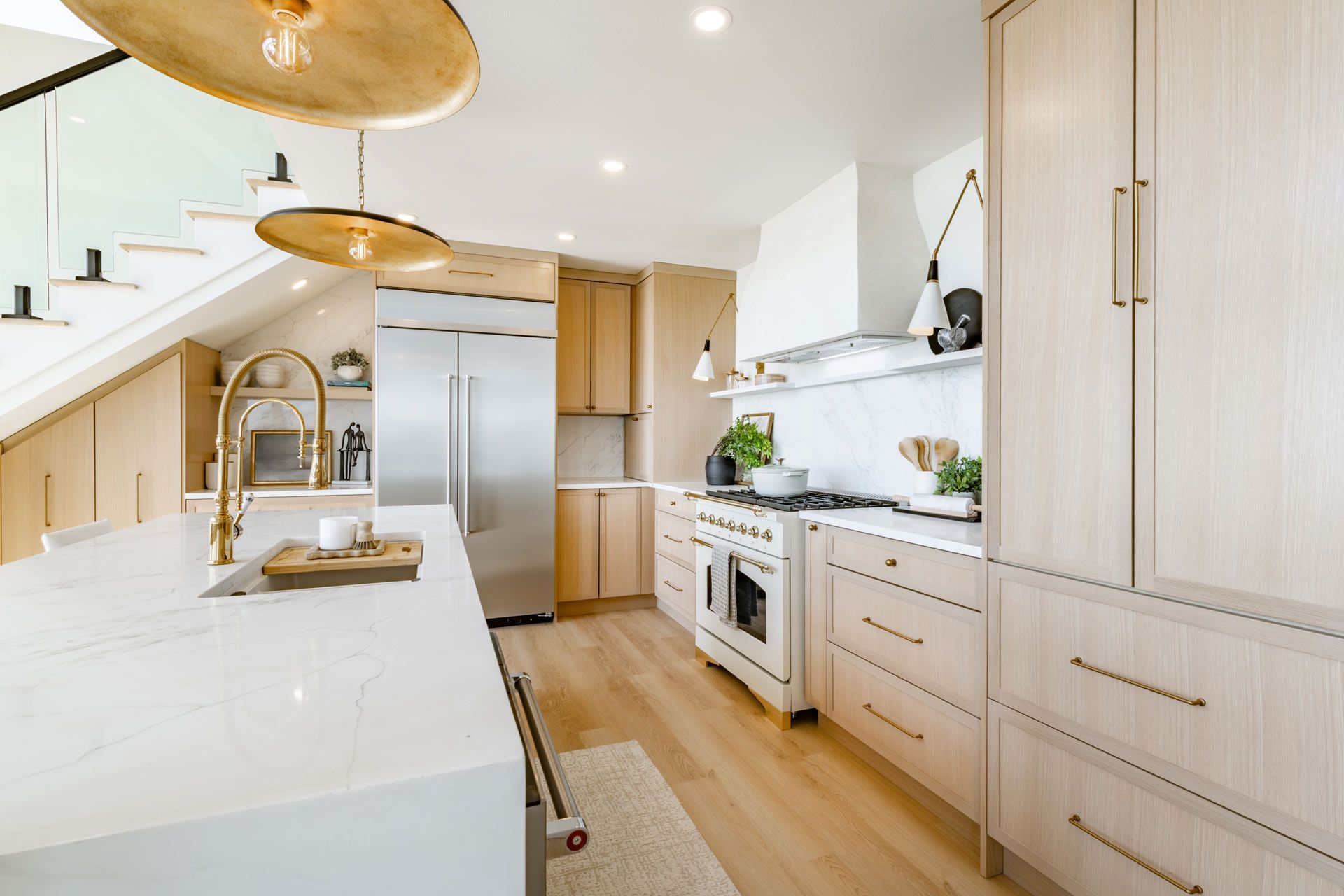 Modern kitchen with light wood cabinets, stainless steel appliances, and white countertops.