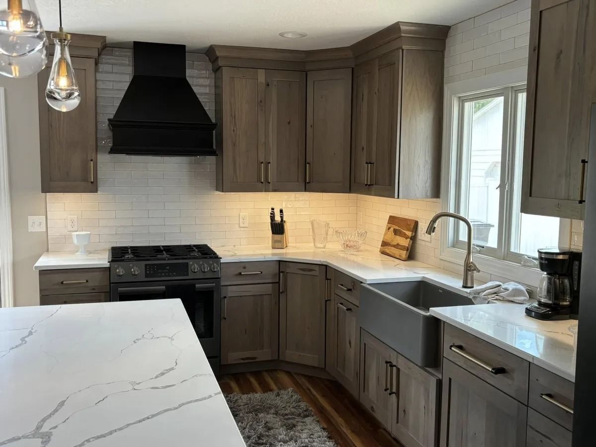 Kitchen with gray wood cabinets, white countertops, stainless steel sink, and black stove range.