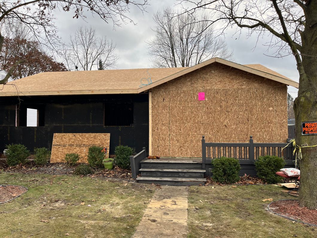House under construction with wood siding and new roof; cloudy sky.