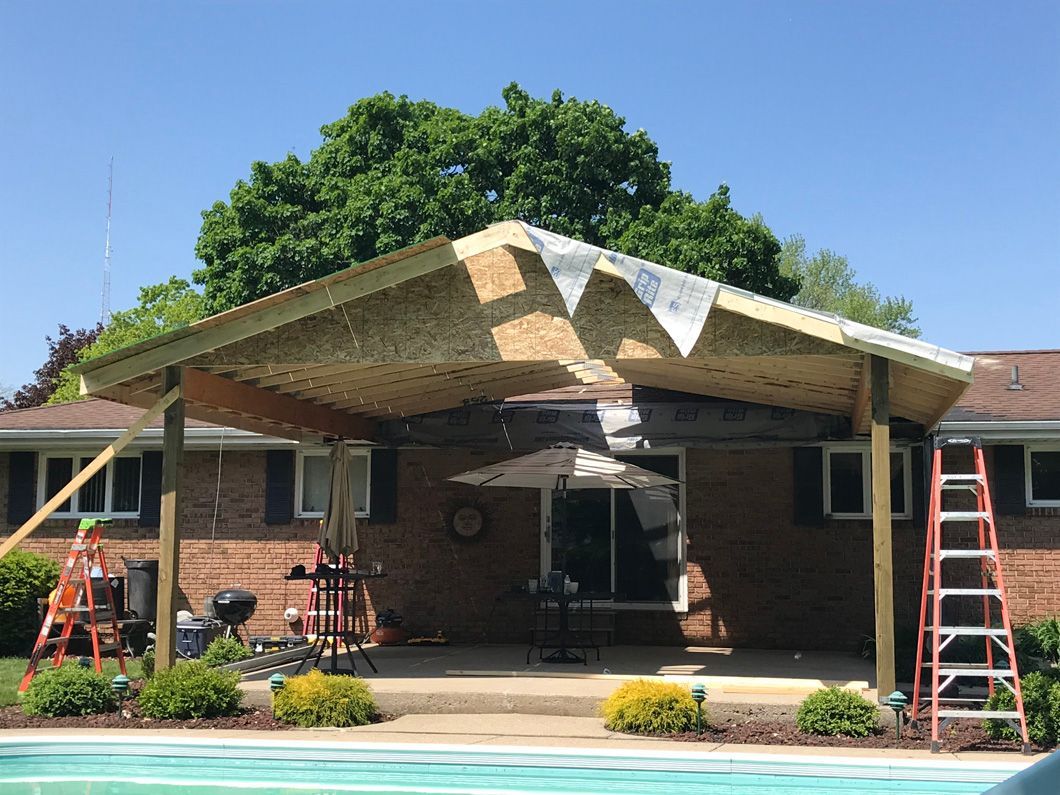 Backyard patio with a new wooden roof under construction.