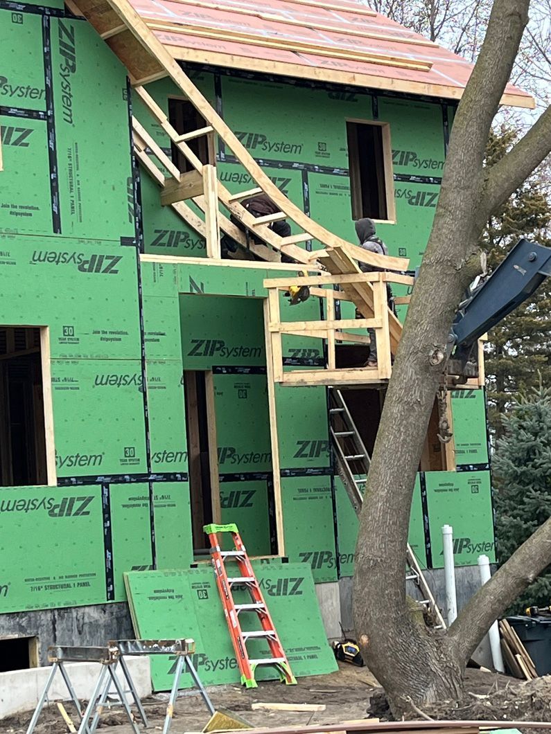 Construction site with green exterior wall, wooden frame structure, and an extended ramp.