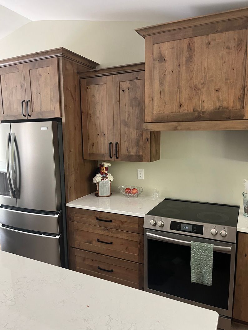 Kitchen with rustic wood cabinets, stainless steel appliances, and a white countertop.