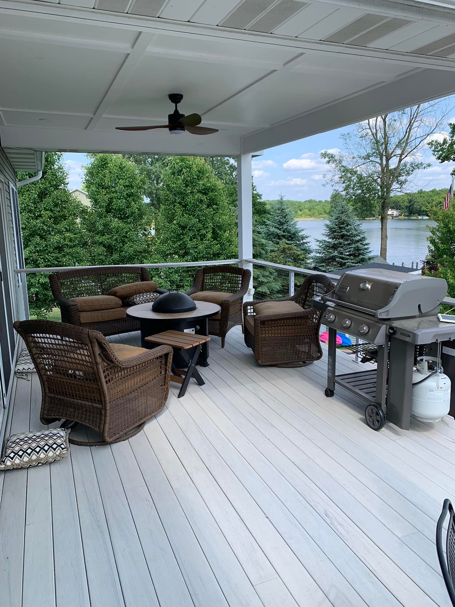 Patio with wicker furniture, grill, and a lake view.