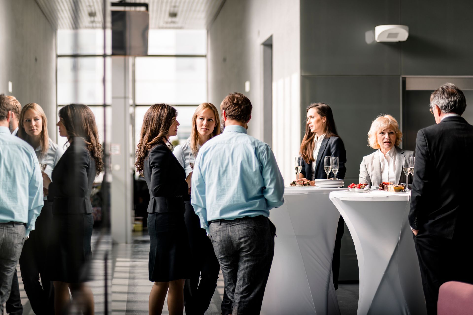 People networking at an event, gathered around high tables, talking.