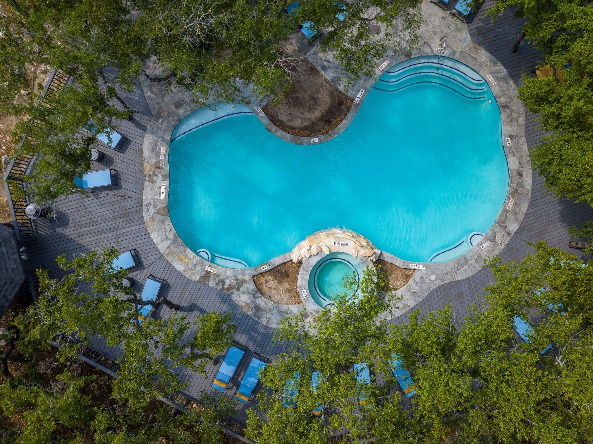 An aerial view of a large swimming pool surrounded by trees and chairs at Allure at Shavano.