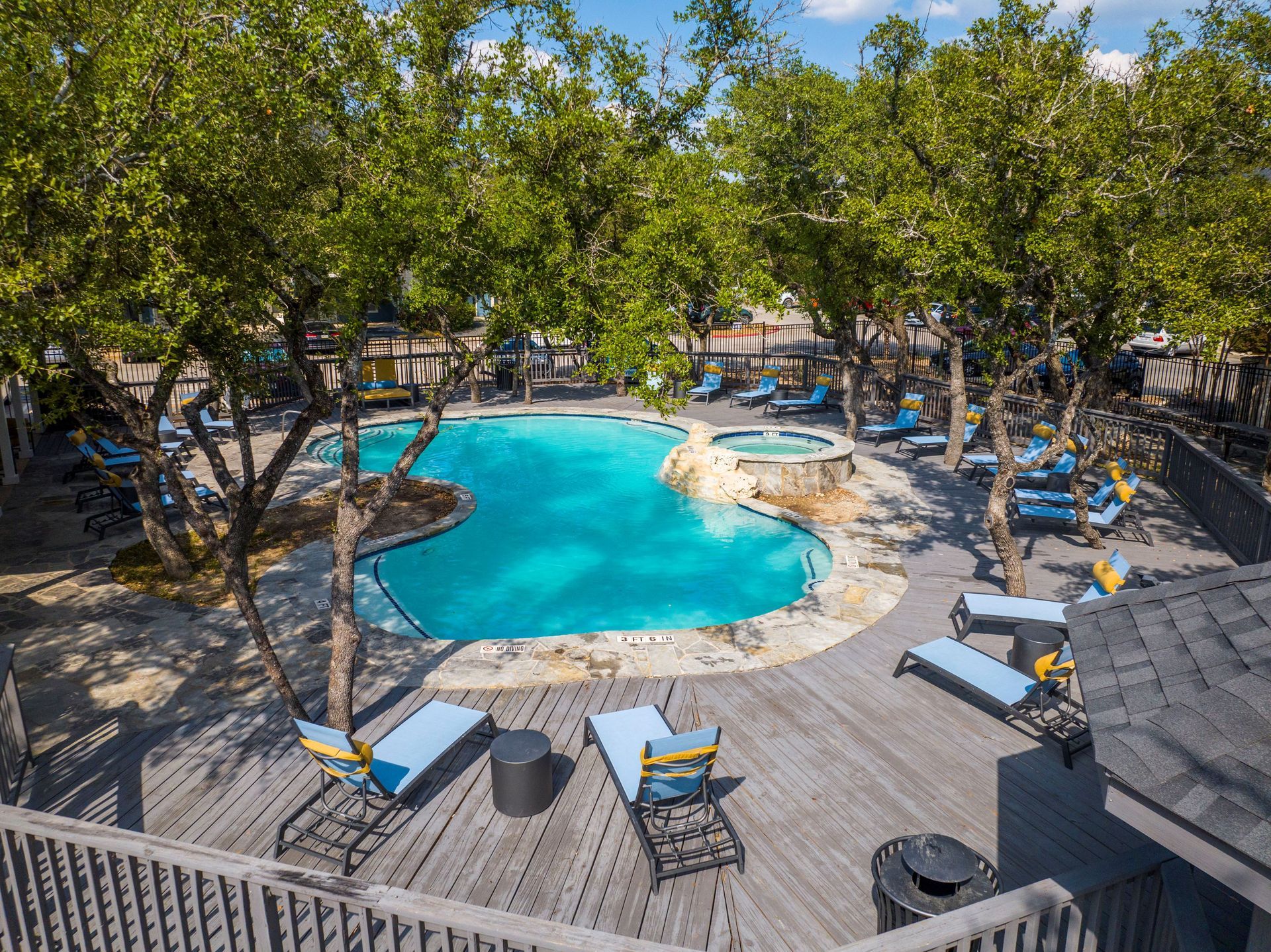 An aerial view of a large swimming pool surrounded by trees and chairs at Allure at Shavano.
