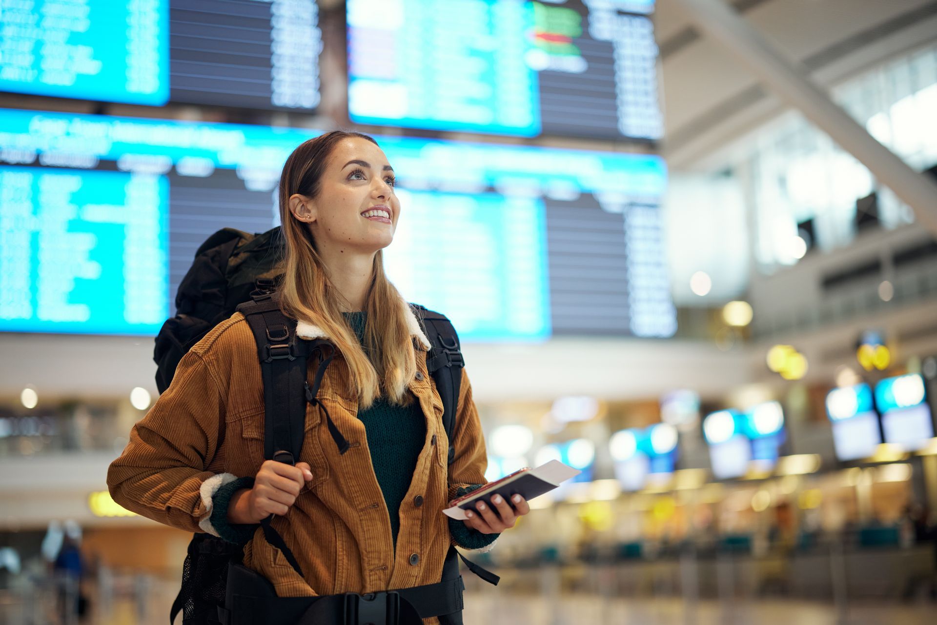 Traveler with a backpack checking flight information at an airport departure board.