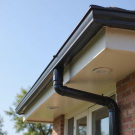 Black gutter system on a house with a white soffit and brick exterior.