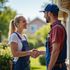 Woman in overalls shakes hands with a worker in front of a house.