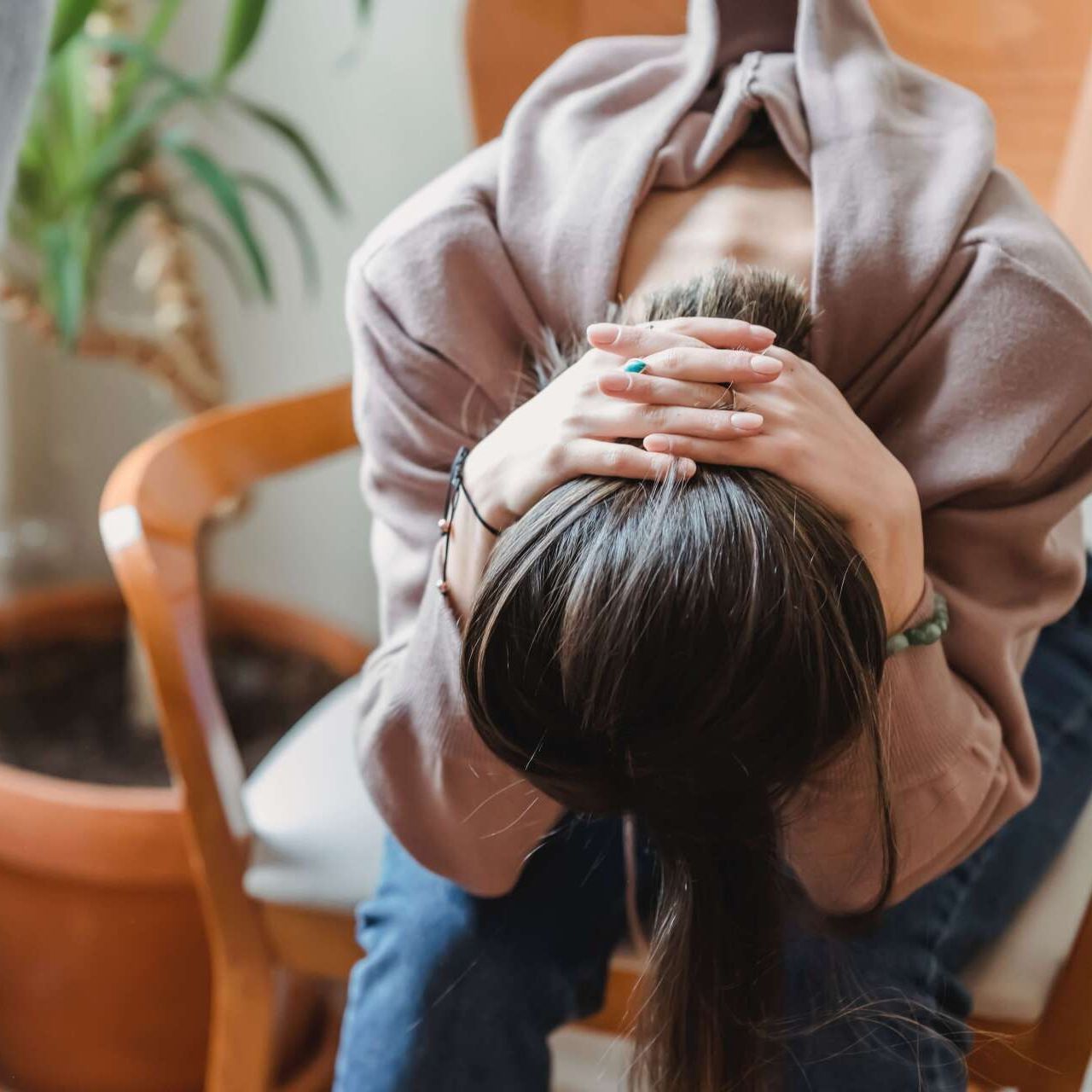 A woman is sitting in a chair with her head in her hands