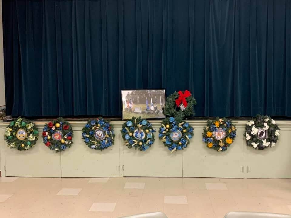 A row of christmas wreaths are sitting on a table in front of a blue curtain.
