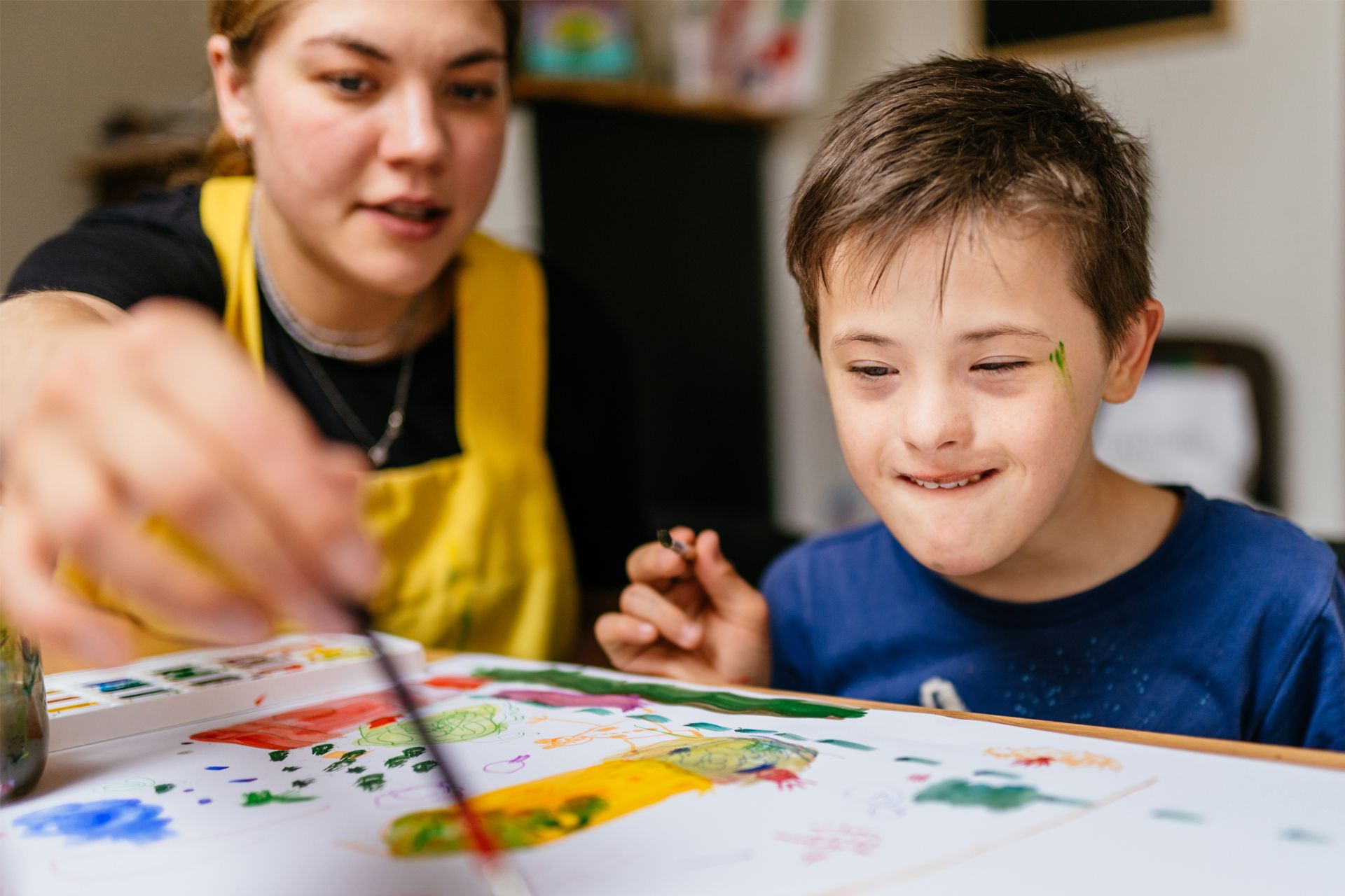 Child With Down Syndrome Painting With Her Caregiver