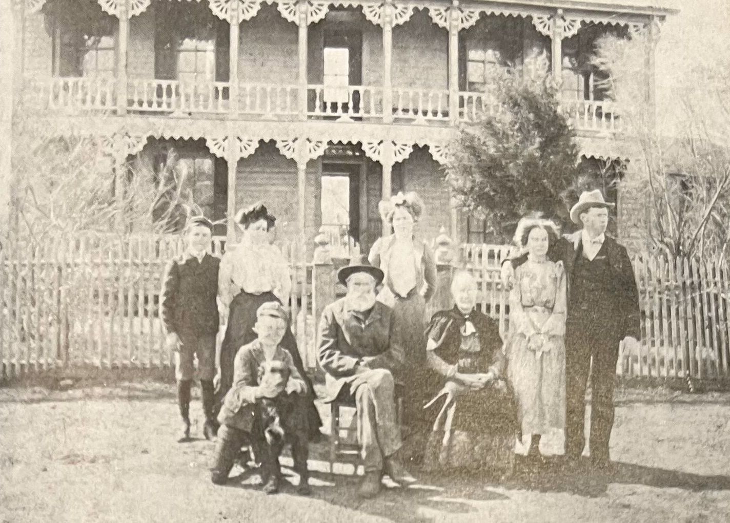 A group of people are posing for a picture in front of a house.