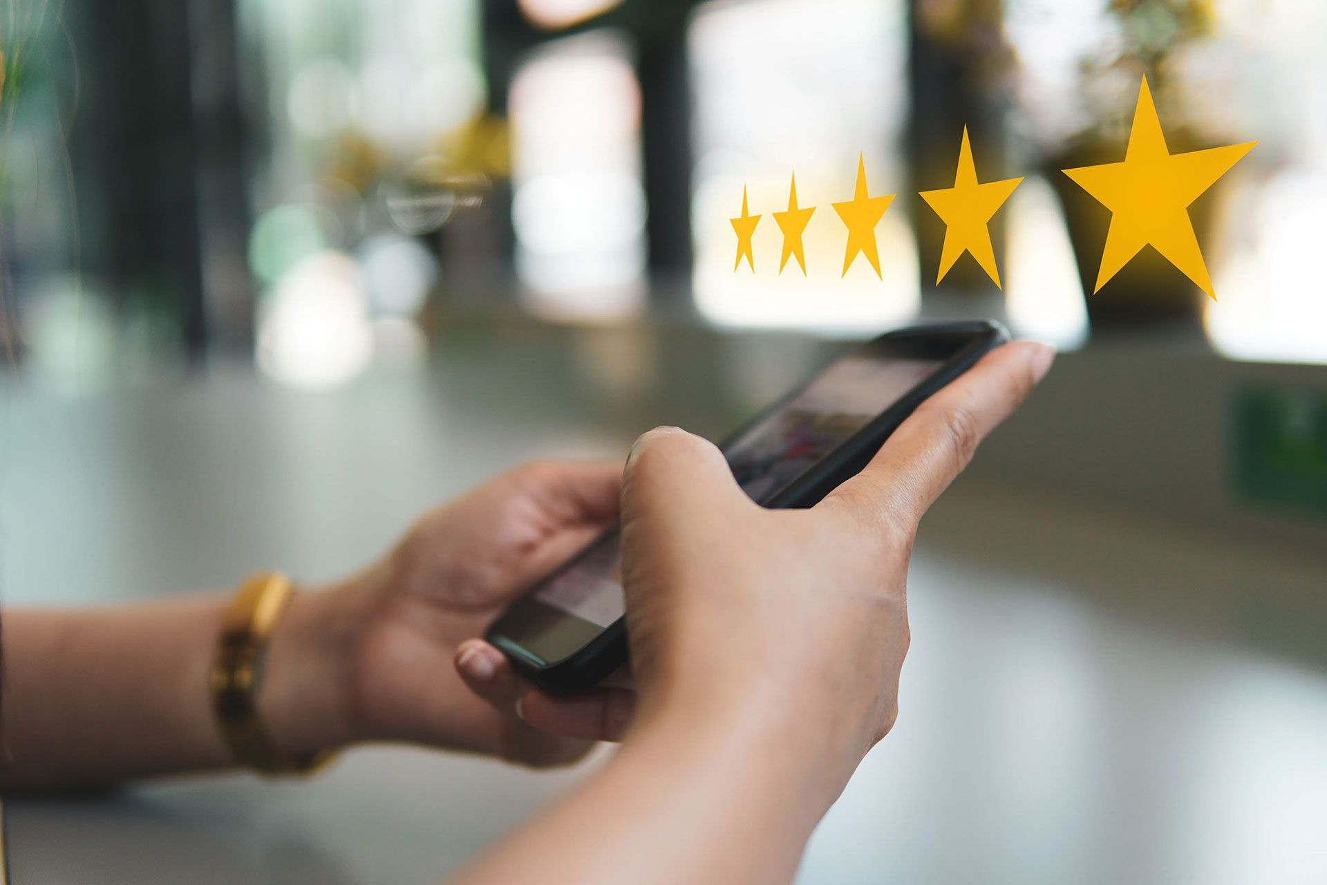 A person is holding a cell phone with three stars on it.