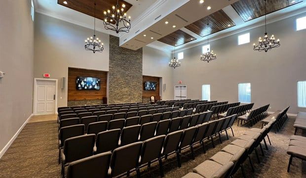 A large auditorium filled with rows of chairs and chandeliers.