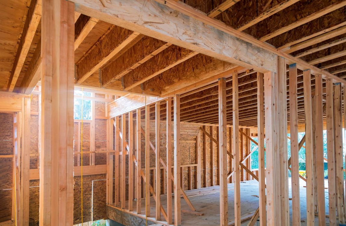 Wooden house framing interior with sunlight shining in from a window.