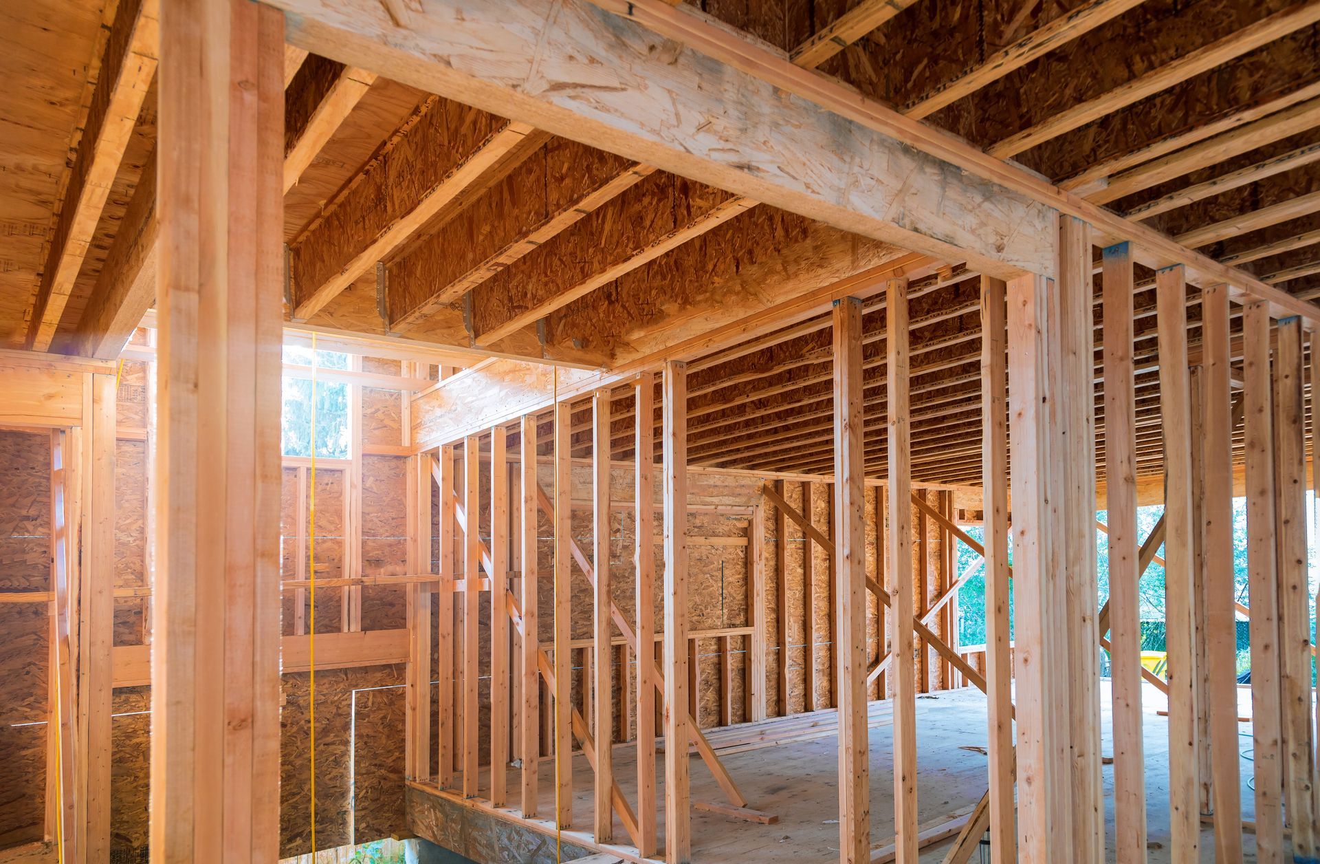 Wooden house framing interior with sunlight shining in from a window.