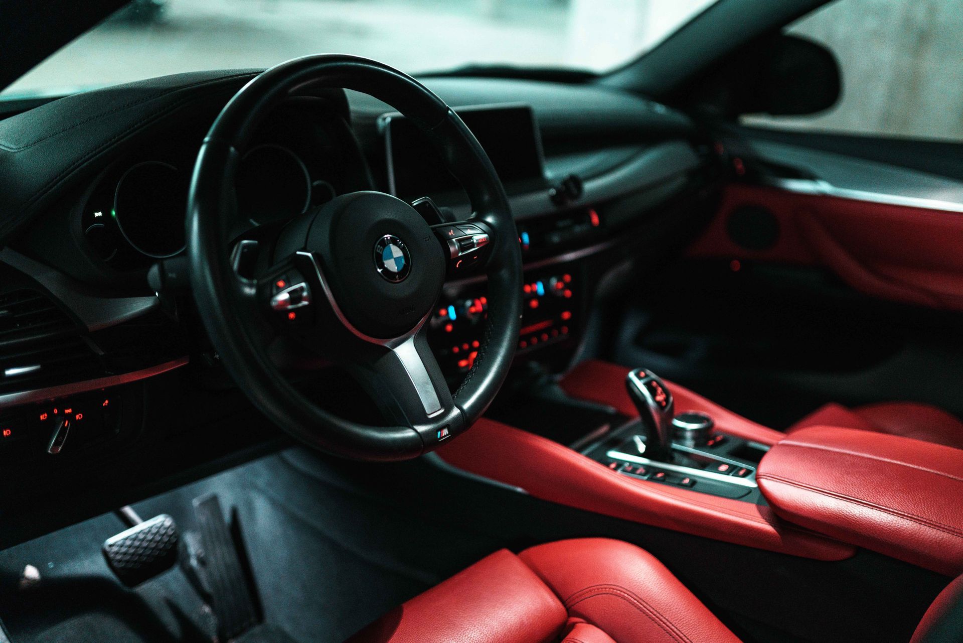 Person wiping a glossy black sports car with a white cloth in a dim garage