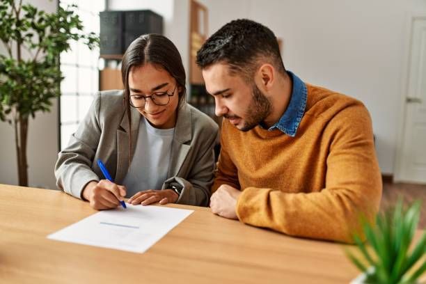 A couple is reviewing and signing a document together.