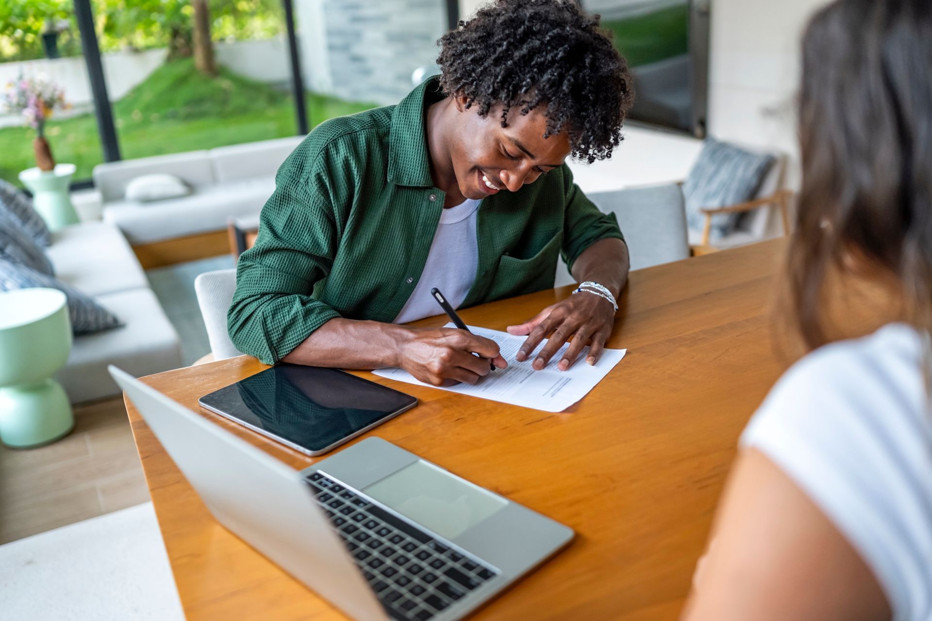 A woman is signing a document in an office in front of another woman.