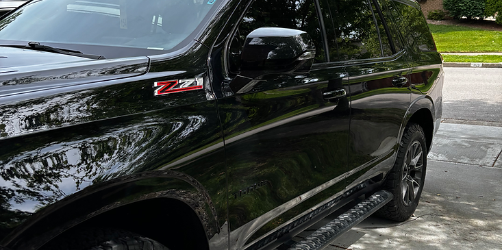 Black sedan parked on a wet street, viewed from the front side.