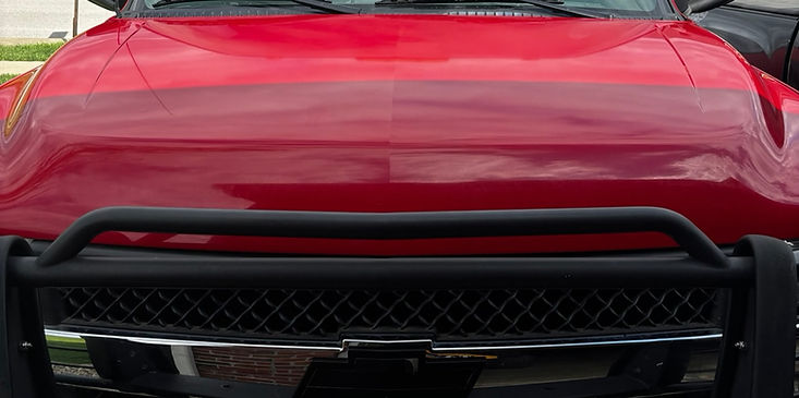 Red car hood with black grille and front bull bar close-up.