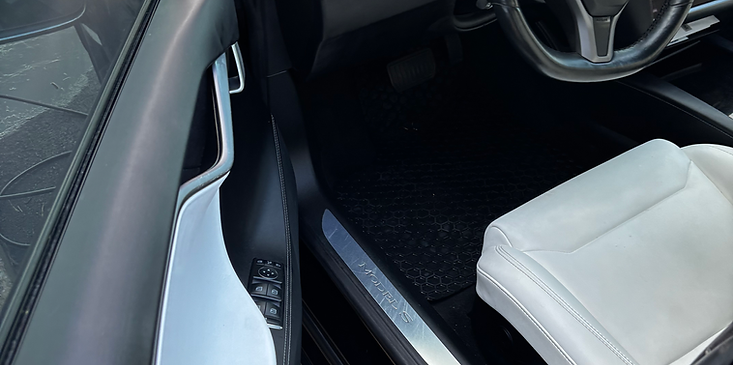 Car interior with white seat and silver trim, showing the front passenger area and dashboard edge
