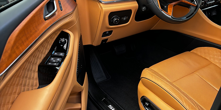 Luxury car interior with tan leather seats, wood trim, and steering wheel visible