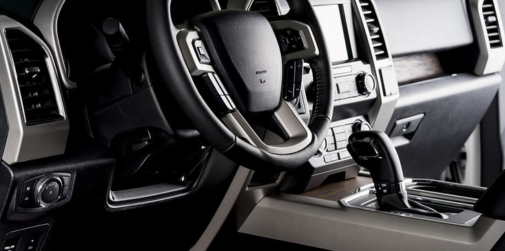 Black car interior with steering wheel, dashboard controls, and center console gear shifter
