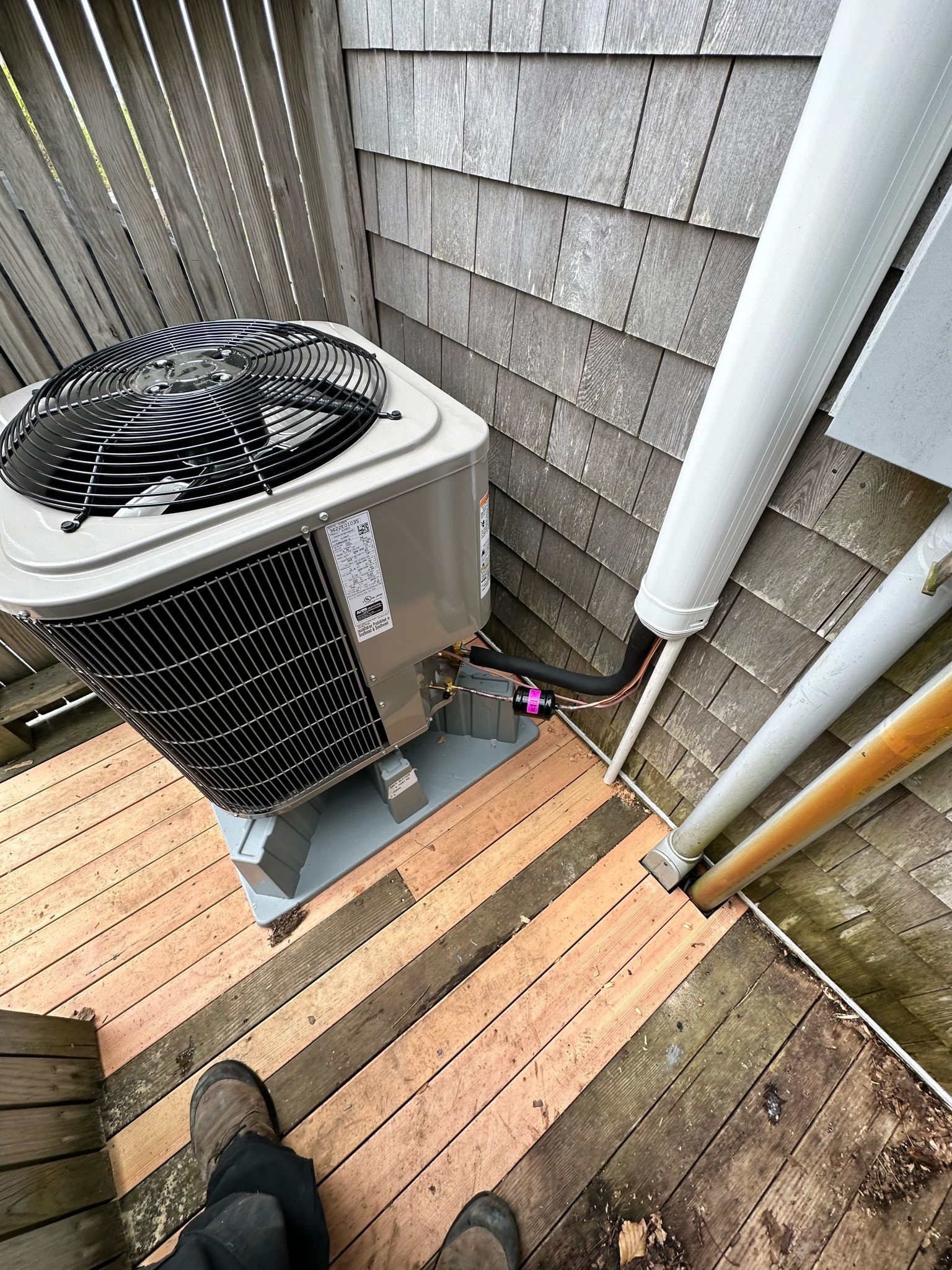 Air conditioning unit next to weathered wooden steps and siding.