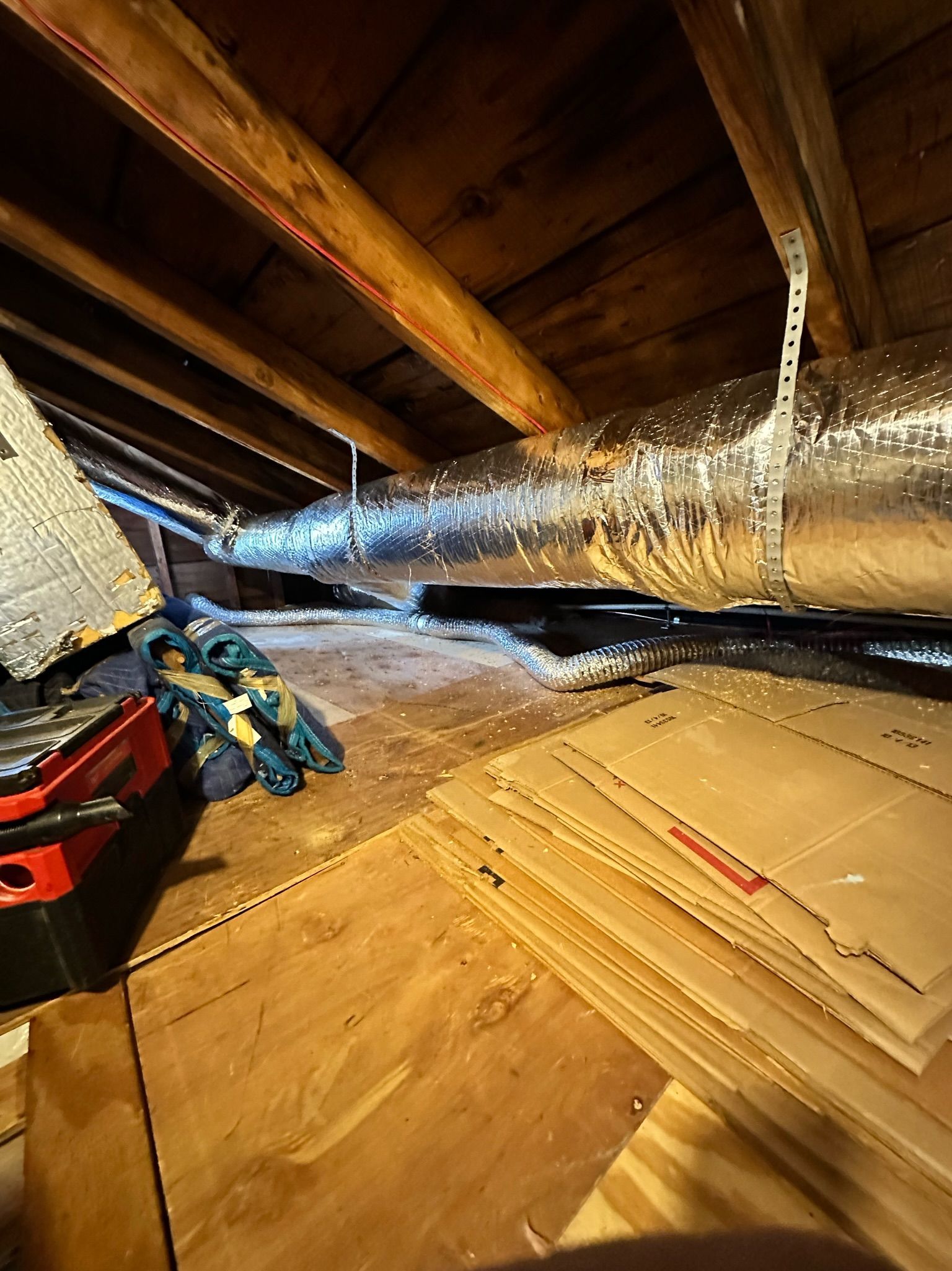 Attic space with plywood, HVAC ducting, and wooden beams.