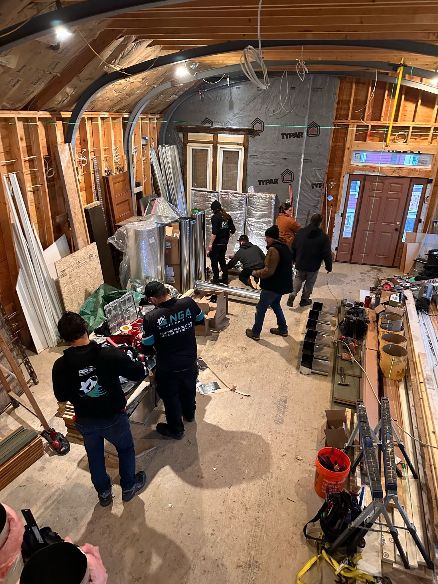 Construction site with workers inside a building. Walls are framed; debris and materials are present.