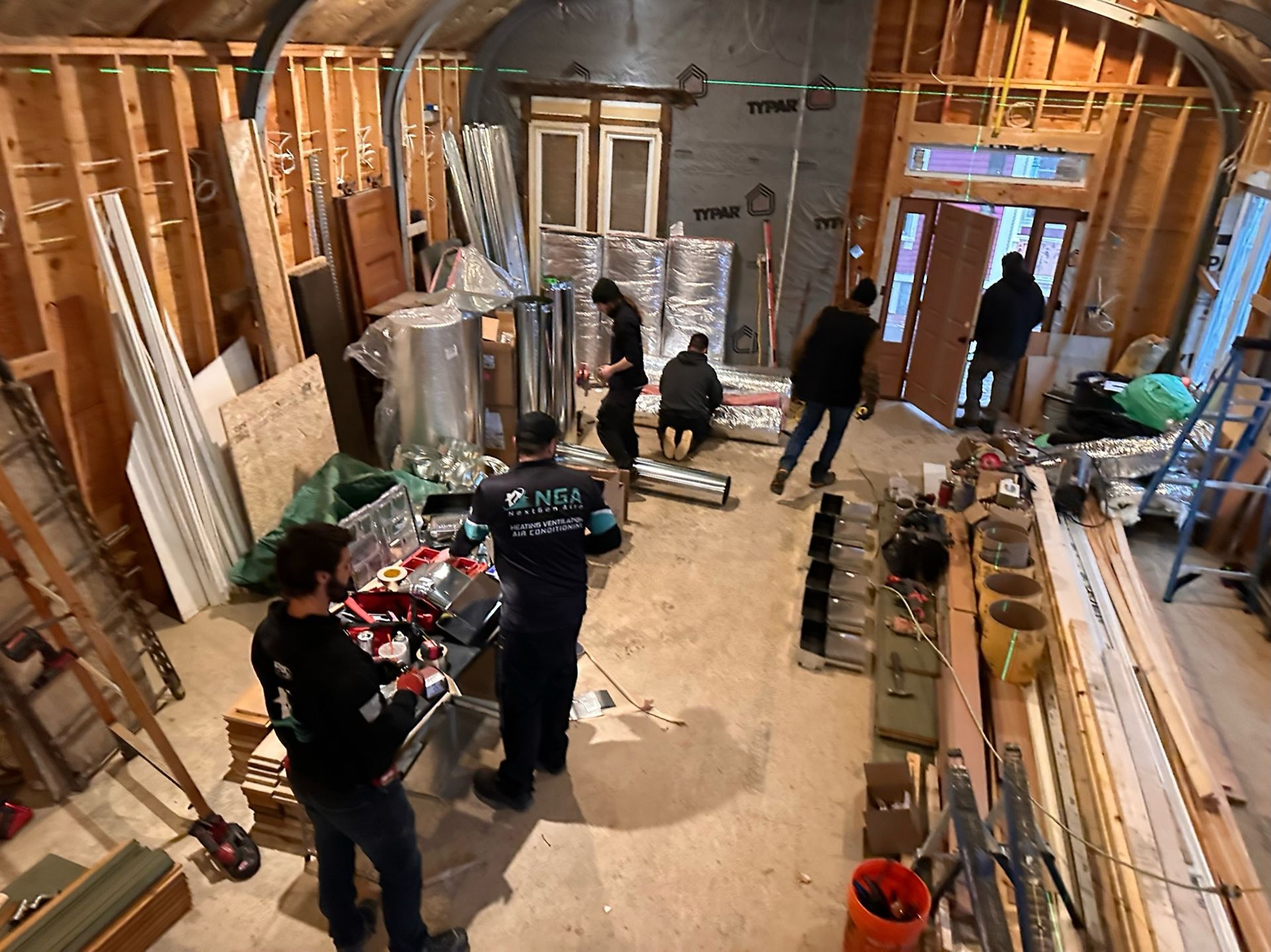Construction crew working inside a room with exposed framing, tools, and insulation.