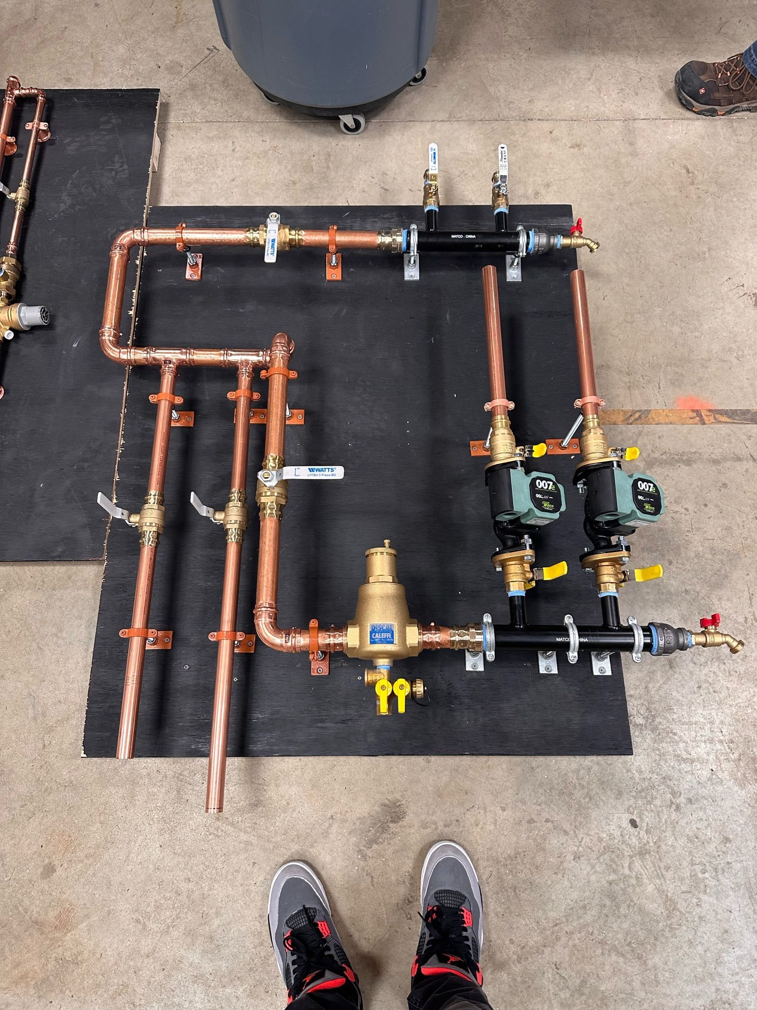 Copper pipes and valves, pre-assembled on a black board, viewed from above.