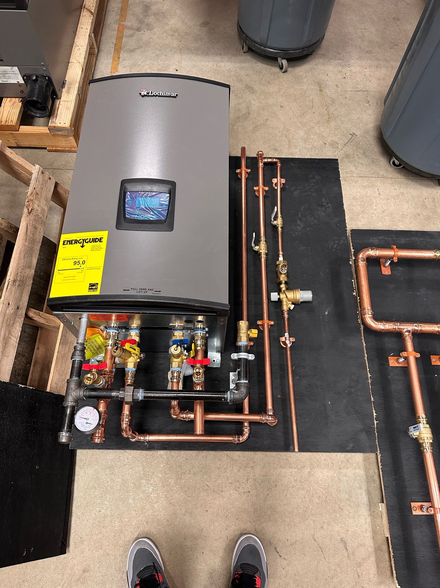 Tankless water heater with copper pipes, valves, and a small display, ready for installation.