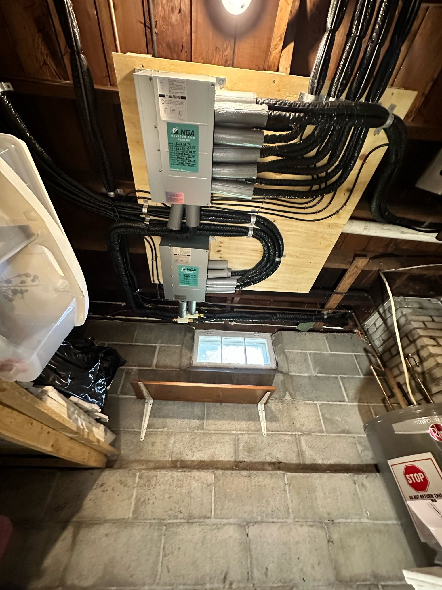 Electrical equipment mounted on wood panel in a basement. Wires and cinder block wall visible.